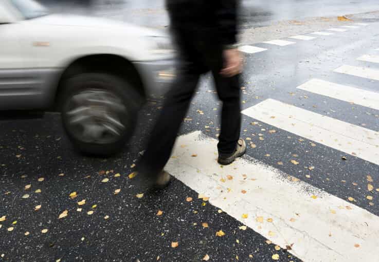 car speeds toward a pedestrian in a crosswalk